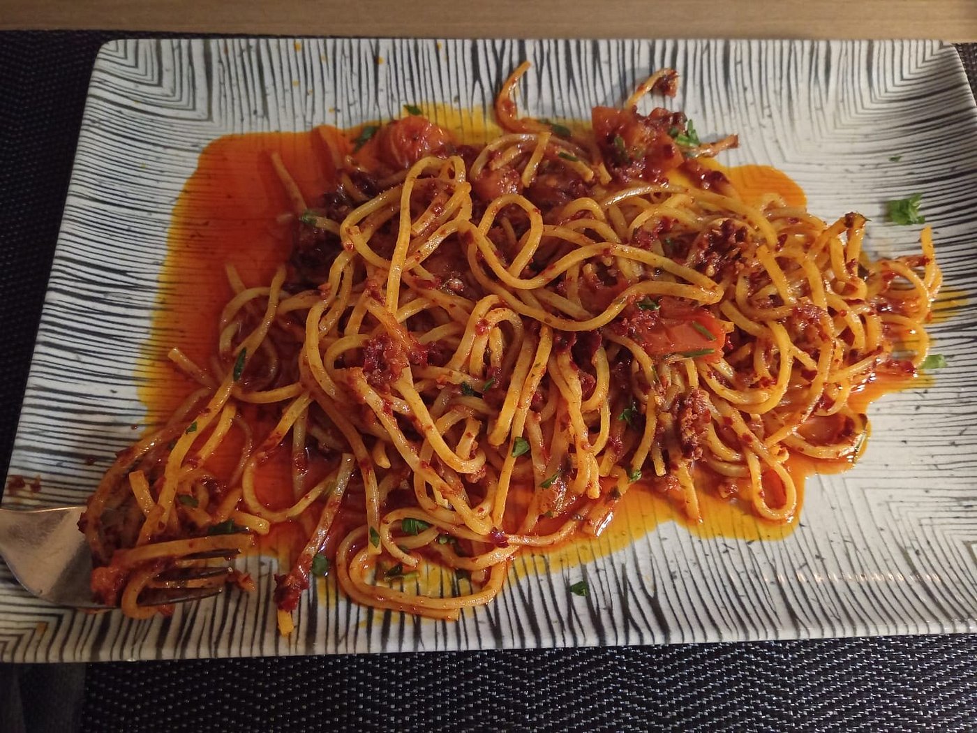 Linguine al sugo piccante con frutti di mare y tomate sobre plato rectangular