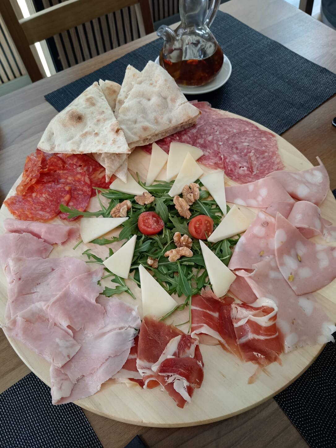 Tabla de embutidos italianos con salami, mortadela, jamón, quesos, rúcula y nueces